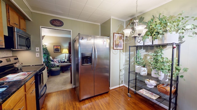 kitchen with hardwood / wood-style flooring, pendant lighting, stainless steel appliances, and a chandelier