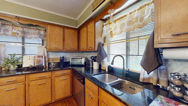 kitchen featuring sink, tasteful backsplash, dark stone counters, stainless steel dishwasher, and ornamental molding