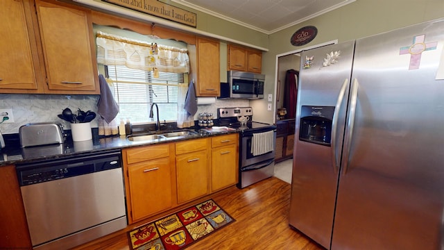 kitchen featuring appliances with stainless steel finishes, crown molding, tasteful backsplash, hardwood / wood-style flooring, and sink