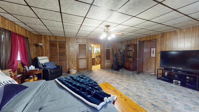 bedroom with wooden walls, carpet flooring, and ceiling fan