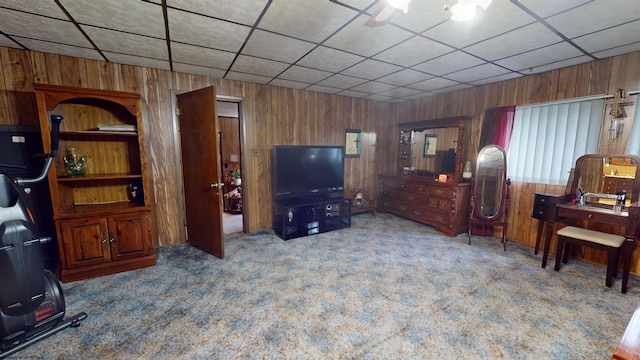 living room featuring ceiling fan, wooden walls, and carpet flooring