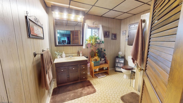 bathroom featuring wood walls, vanity, toilet, and tile flooring