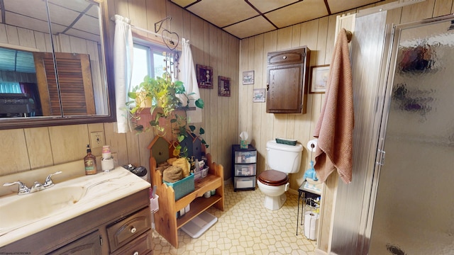 bathroom with wooden walls, tile floors, toilet, a shower with shower door, and vanity