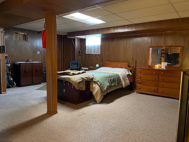 carpeted bedroom featuring a drop ceiling and wood walls