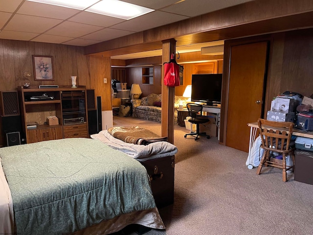 carpeted bedroom featuring a drop ceiling and wooden walls