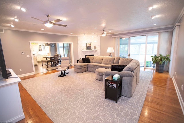 living room featuring ceiling fan, crown molding, and light wood-type flooring