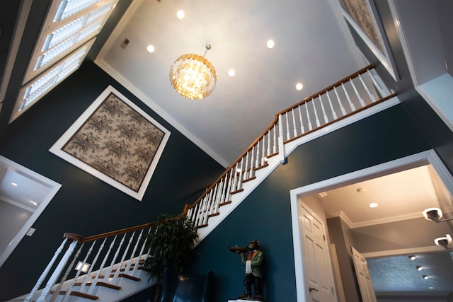 staircase with a high ceiling, a chandelier, and crown molding