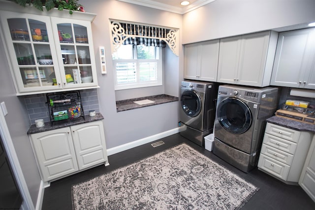 laundry area with ornamental molding, dark wood-type flooring, washing machine and dryer, and cabinets