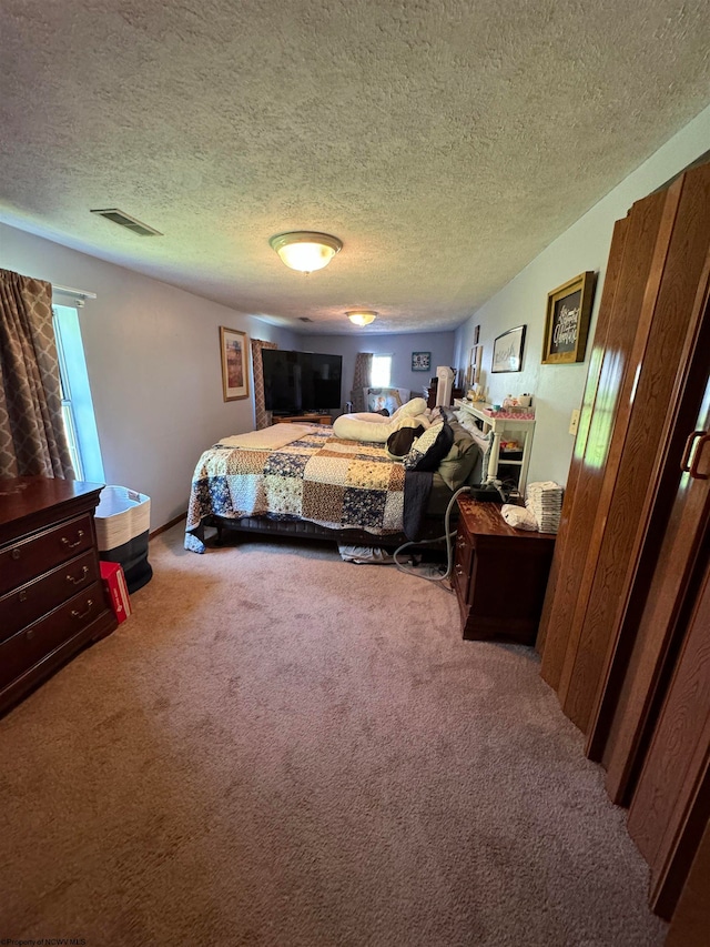 bedroom featuring carpet flooring, visible vents, and a textured ceiling