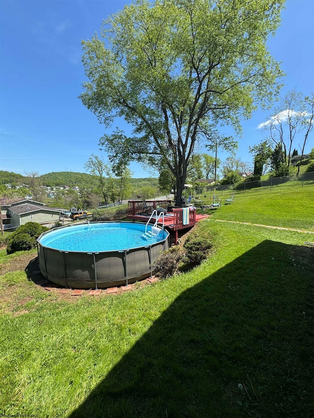 pool featuring a lawn, a deck with mountain view, and fence