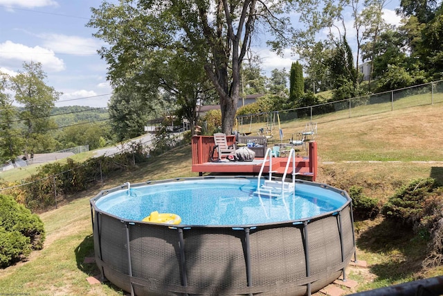 view of pool featuring a wooden deck, a lawn, fence, and a fenced in pool