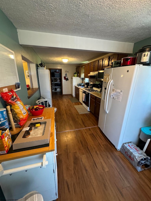 kitchen featuring a textured ceiling, light countertops, white appliances, and dark wood-style flooring