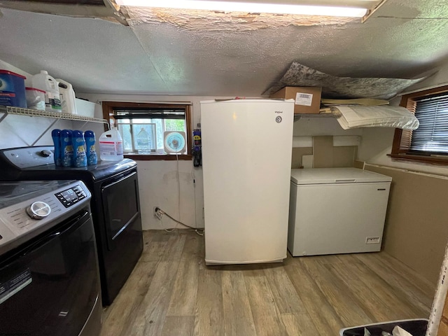 washroom featuring light hardwood / wood-style floors, washing machine and dryer, and a textured ceiling