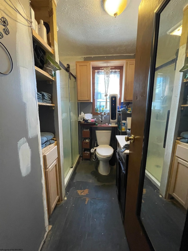 bathroom with walk in shower, vanity, toilet, and a textured ceiling