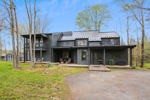 view of front of home with a deck, a shed, and a front yard