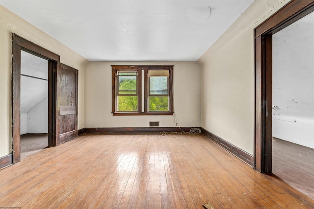 spare room with wood-type flooring and vaulted ceiling