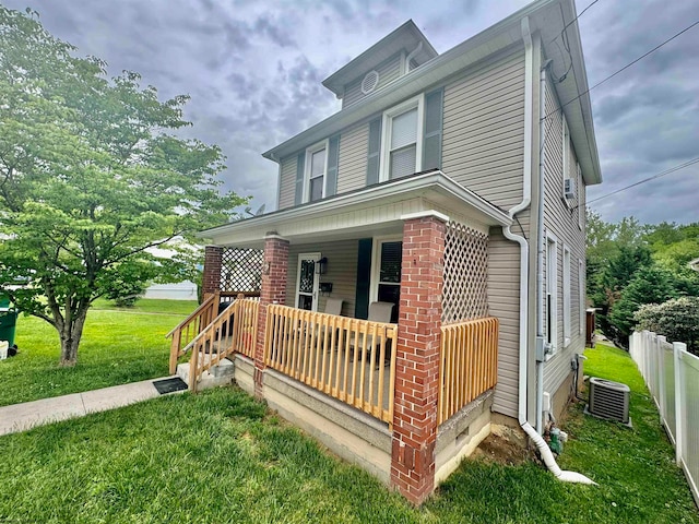 view of front property featuring a porch, central AC unit, and a front yard