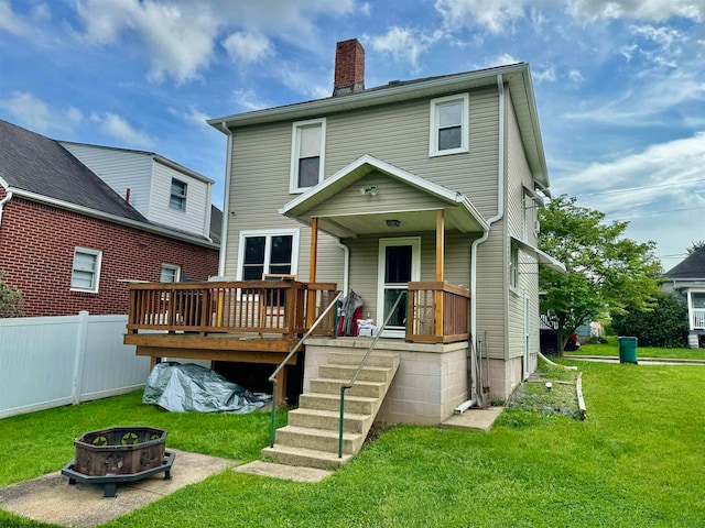 rear view of house with a wooden deck, a fire pit, and a yard