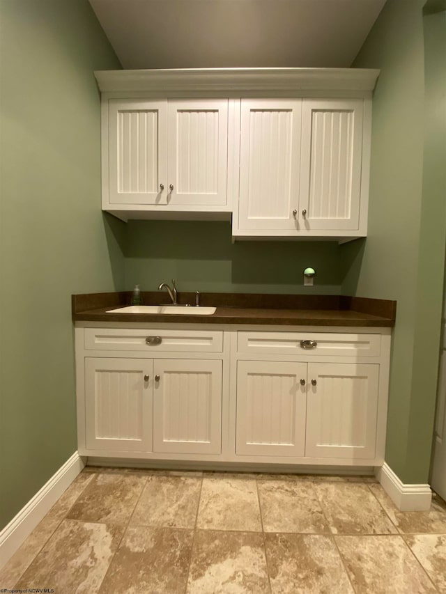 laundry area featuring sink and light tile flooring