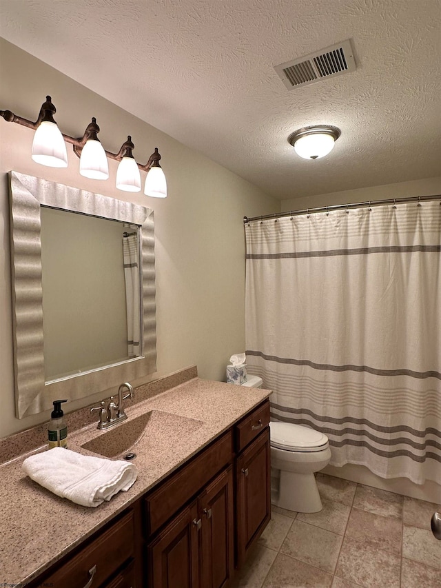 bathroom featuring tile floors, toilet, large vanity, and a textured ceiling