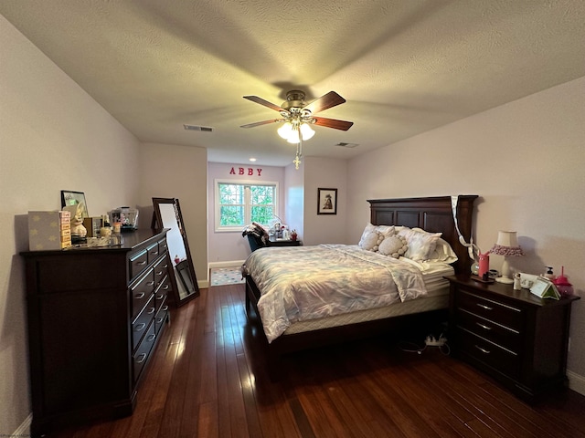 bedroom featuring dark wood-type flooring, ceiling fan, and a textured ceiling