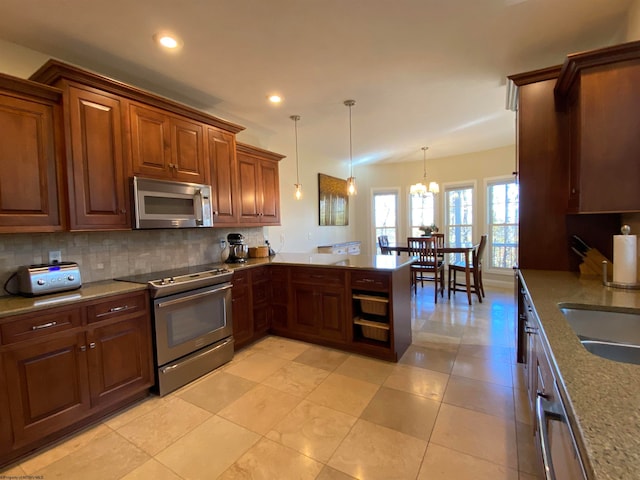 kitchen featuring kitchen peninsula, decorative light fixtures, stainless steel appliances, light tile flooring, and an inviting chandelier