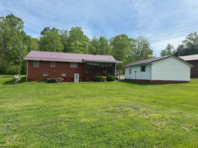 rear view of property featuring a lawn and a sunroom