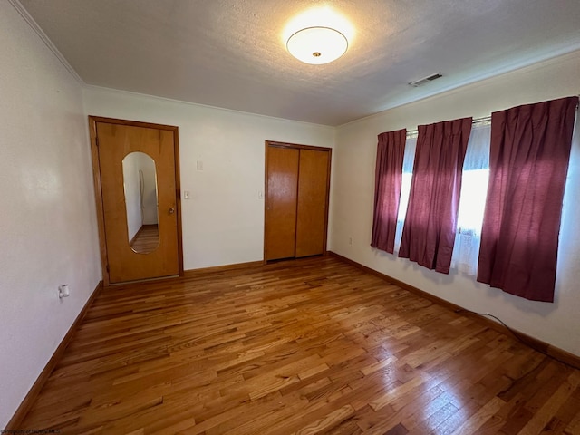 unfurnished bedroom featuring wood-type flooring, a textured ceiling, and a closet