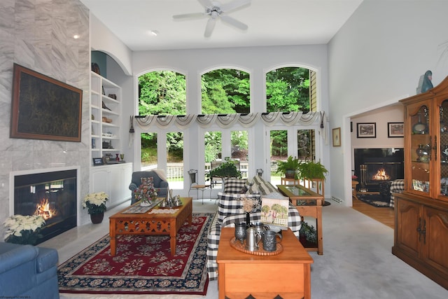 living room with built in shelves, a high end fireplace, ceiling fan, and carpet floors