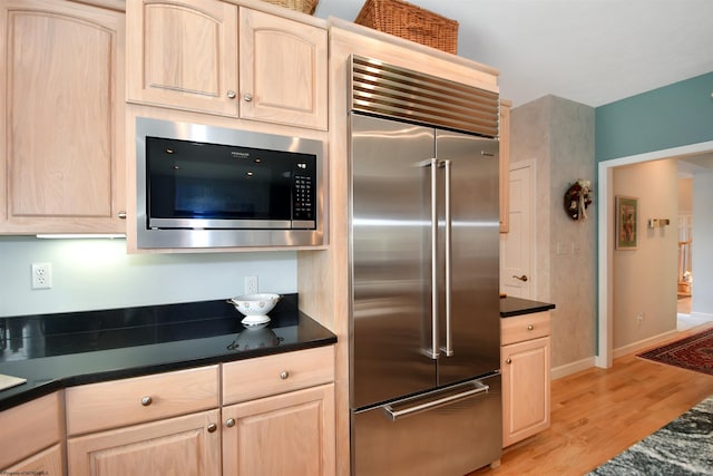 kitchen featuring built in appliances, light hardwood / wood-style flooring, and light brown cabinets