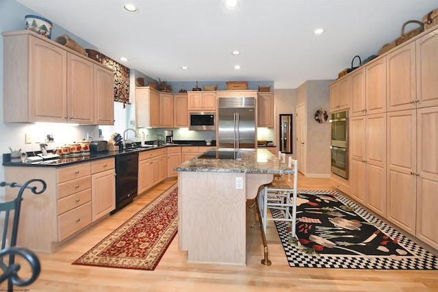 kitchen featuring light hardwood / wood-style flooring, a kitchen island, black appliances, and a breakfast bar