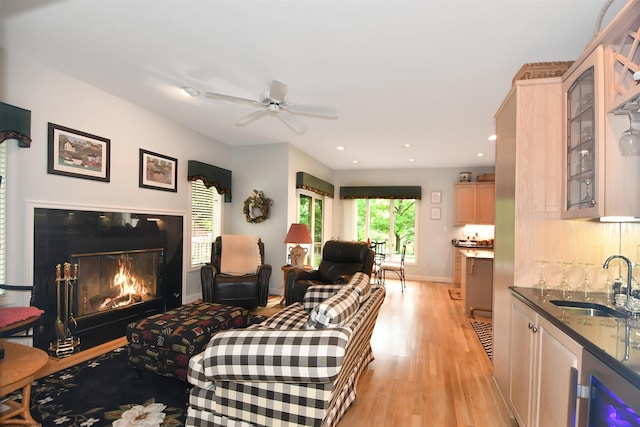 living room with light hardwood / wood-style flooring, ceiling fan, and sink