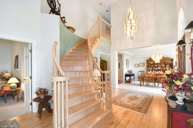 entrance foyer featuring hardwood / wood-style floors, a chandelier, and a high ceiling