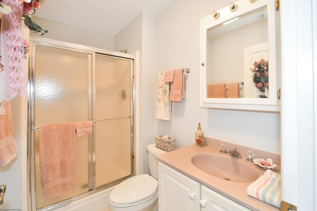 bathroom with vanity with extensive cabinet space, an enclosed shower, and toilet