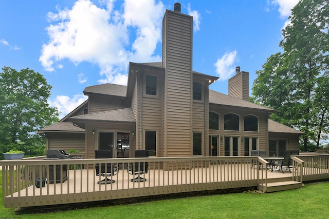 back of house with a deck and a lawn