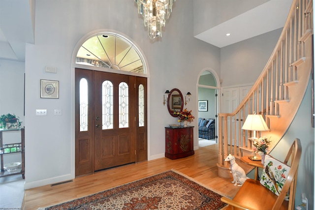 foyer with hardwood / wood-style flooring, a high ceiling, and a chandelier