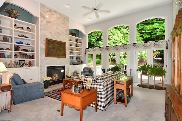 living room with ceiling fan, carpet flooring, a high end fireplace, and built in shelves