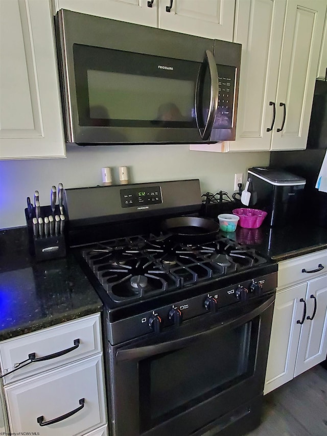 kitchen featuring black gas stove, white cabinetry, and dark stone countertops