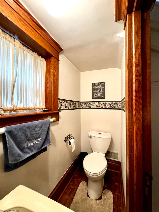 bathroom featuring parquet flooring and toilet