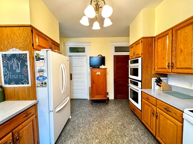 kitchen with hanging light fixtures, white refrigerator, stainless steel double oven, backsplash, and a chandelier