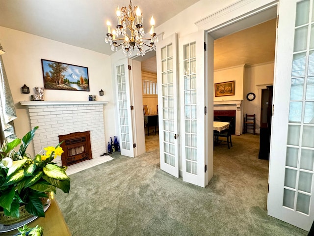 living room with french doors, crown molding, a brick fireplace, carpet, and a chandelier