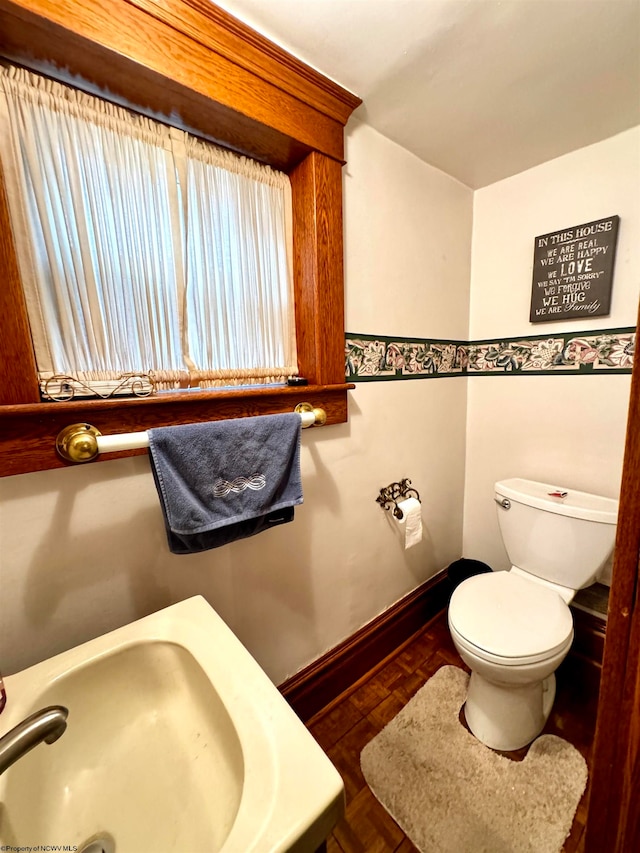 bathroom featuring parquet flooring and toilet