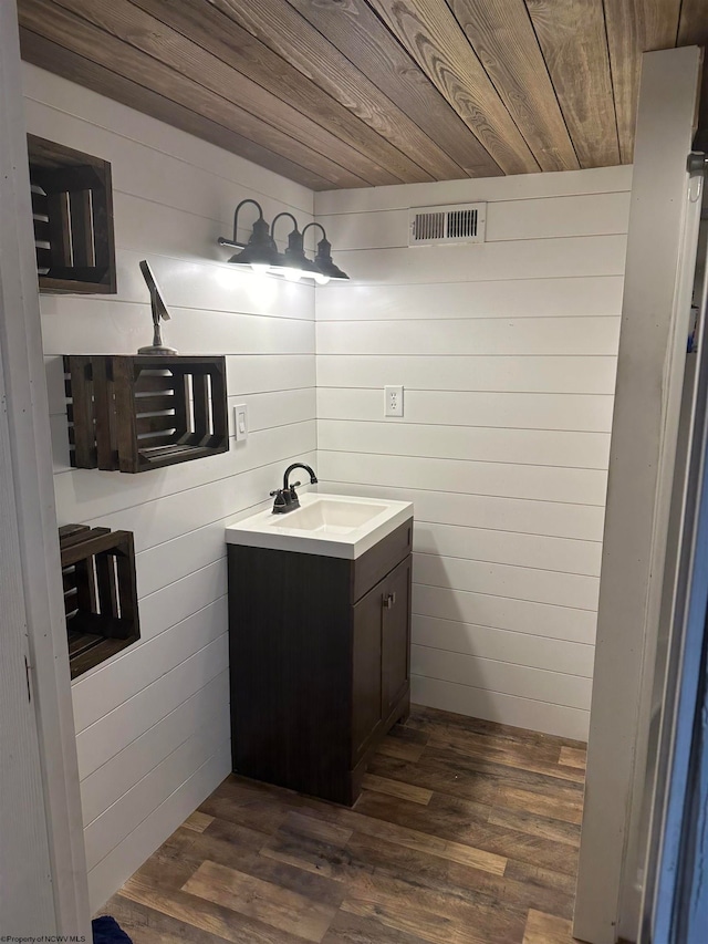 bathroom with wood walls, hardwood / wood-style flooring, wood ceiling, and vanity