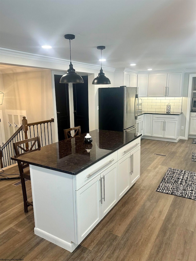 kitchen featuring white cabinets, tasteful backsplash, stainless steel fridge, and hardwood / wood-style flooring