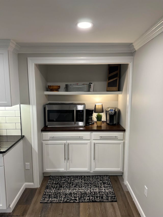 interior space with dark wood-type flooring, white cabinetry, ornamental molding, and tasteful backsplash