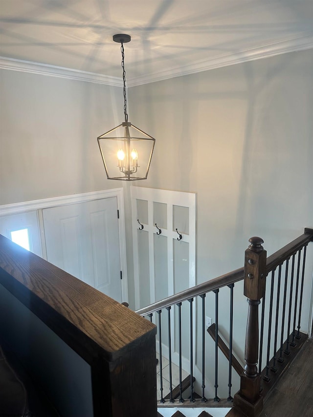 stairs featuring ornamental molding, an inviting chandelier, and dark hardwood / wood-style flooring