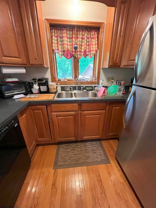 kitchen with dishwasher, light hardwood / wood-style floors, sink, and stainless steel refrigerator