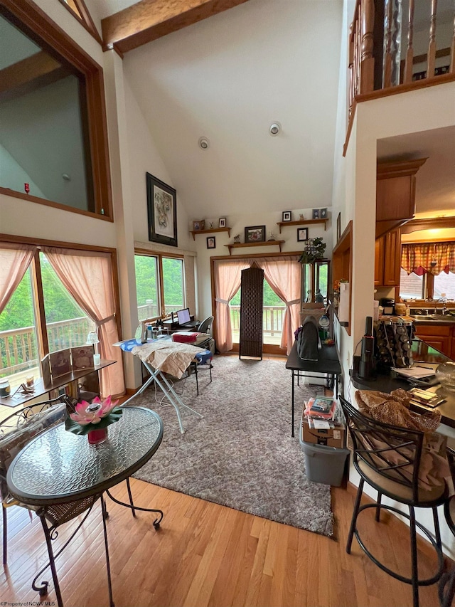 living room with beamed ceiling, hardwood / wood-style flooring, high vaulted ceiling, and sink