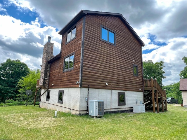 view of side of home with central AC and a yard