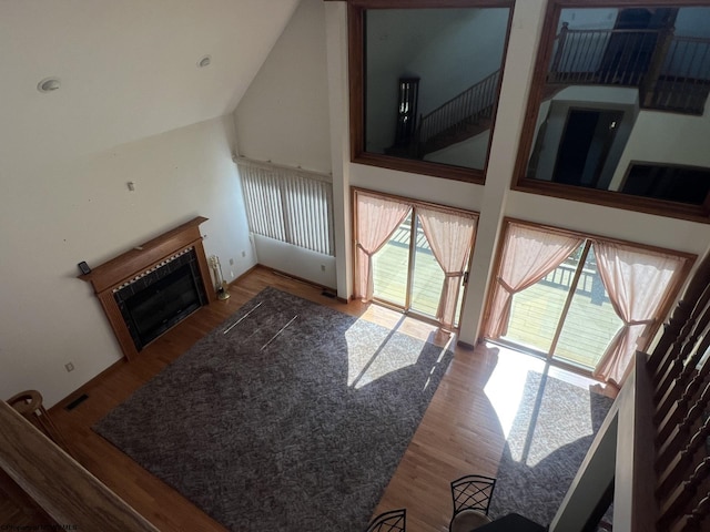 living room with a tile fireplace, high vaulted ceiling, and wood-type flooring